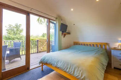 a bedroom with a bed and a balcony with a television at Pod2 - Powys River Pods - Pet Friendly Glamping Pod Builth Wells Powys Wales in Garth