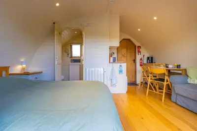 a bedroom with a bed and a kitchen and a table at Pod2 - Powys River Pods - Pet Friendly Glamping Pod Builth Wells Powys Wales in Garth