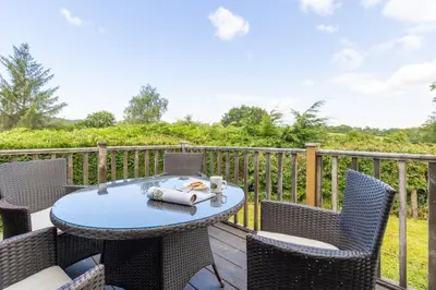 a patio with a table and chairs on a deck at Pod2 - Powys River Pods - Pet Friendly Glamping Pod Builth Wells Powys Wales in Garth