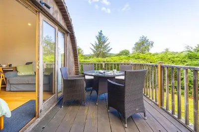 a patio with a table and chairs on a deck at Pod2 - Powys River Pods - Pet Friendly Glamping Pod Builth Wells Powys Wales in Garth