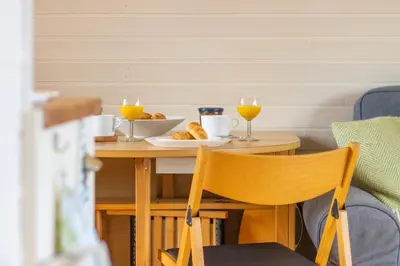 a table with a plate of food and two glasses of orange juice at Pod2 - Powys River Pods - Pet Friendly Glamping Pod Builth Wells Powys Wales in Garth