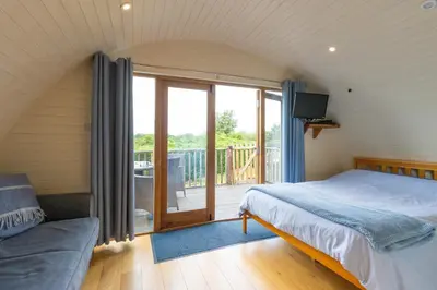 a bedroom with a bed and a balcony at Pod1 - Powys River Pods - Pet Friendly Glamping Pod Builth Wells Powys Wales in Garth