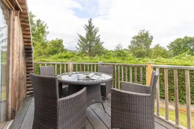 a patio with a table and chairs on a deck at Pod1 - Powys River Pods - Pet Friendly Glamping Pod Builth Wells Powys Wales in Garth