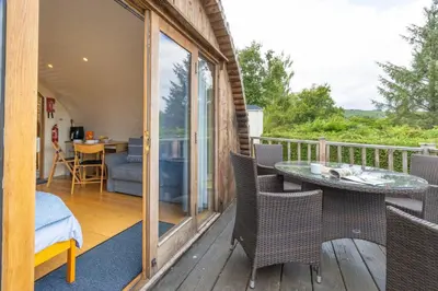 a patio with a table and chairs on a balcony at Pod1 - Powys River Pods - Pet Friendly Glamping Pod Builth Wells Powys Wales in Garth