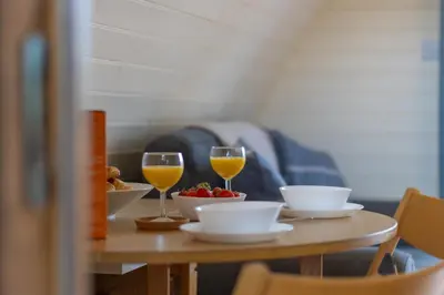 a table with two glasses of wine and a bowl of fruit at Pod1 - Powys River Pods - Pet Friendly Glamping Pod Builth Wells Powys Wales in Garth
