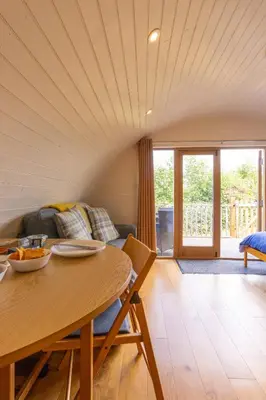 a living room with a table and a couch at Pod3 - Powys River Pods - Pet Friendly Glamping Pod Builth Wells Powys Wales in Garth