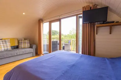 a bedroom with a bed and a tv and a couch at Pod3 - Powys River Pods - Pet Friendly Glamping Pod Builth Wells Powys Wales in Garth