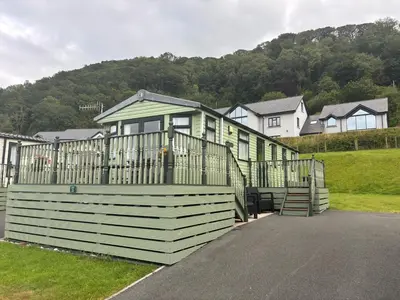a green house with a gate and some houses at Green Heaven at Clarach Bay Spacious 3 BedPet Friendly Luxury Steps from the Sea in Aberystwyth