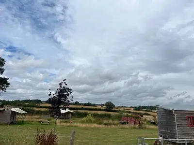 a field with a barn and a cloudy sky at Tinkers Horn Cabin in Kington