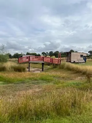 a red bridge in the middle of a field at Tinkers Horn Cabin in Kington