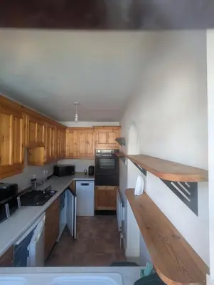 a kitchen with wooden cabinets and white counter tops at Breidden Annexe in Four Crosses