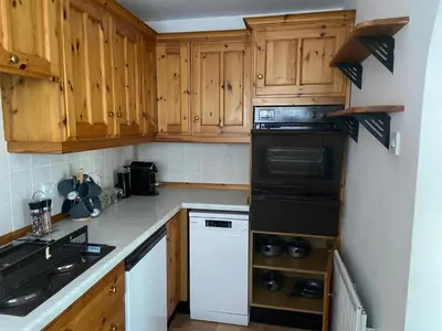 a kitchen with wooden cabinets and a black appliance at Breidden Annexe in Four Crosses