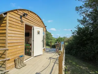 a wooden deck with a building with a door at Squirrel's Drey in Bucknell