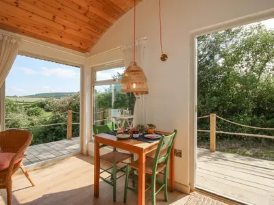 a dining room with a table and chairs on a porch at Squirrel's Drey in Bucknell