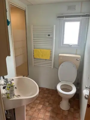 a bathroom with a toilet and a sink and a window at Static Caravan in Aberystwyth