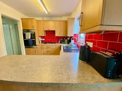 a kitchen with a counter top and red tiles at Your Leominster Base - 3BR Home with Garden & Parking in Leominster