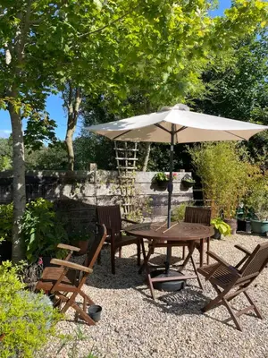 a picnic table and chairs with an umbrella at Y Bwthyn in Llanfihangel-geneuʼr-glyn