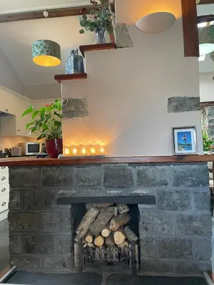 a fireplace in a kitchen with a stone wall at Y Bwthyn in Llanfihangel-geneuʼr-glyn