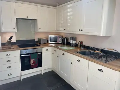 a white kitchen with white cabinets and a sink at Y Bwthyn in Llanfihangel-geneuʼr-glyn