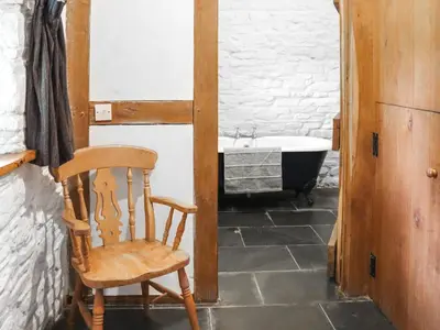 a bathroom with a chair and a bath tub at Thatched Cottage - Uk50261 in Llandeilo