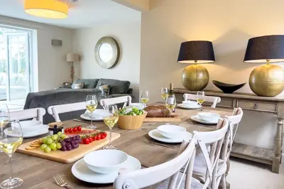 a dining room with a table with food and wine glasses at Wellingtonia Cottage in Chirbury