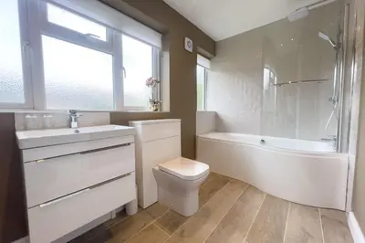 a white bathroom with a tub and a toilet and a sink at Wellingtonia Cottage in Chirbury