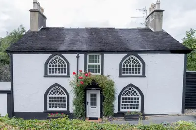 a white house with a black roof at Charming Eco Hideaway on the Dee River with Private Relaxing Hot Tub in Llangollen