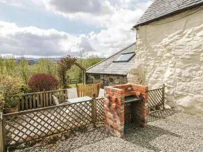 a stone house with a fence and a bench at Cyffdy Cottage - Tegid in Bala