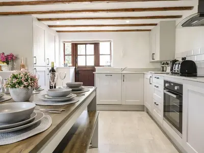 a kitchen with white cabinets and a wooden counter top at Cyffdy Cottage - Arenig in Bala