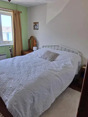 a bedroom with a white bed with a pillow on it at King bed, opposite the beach in Borth
