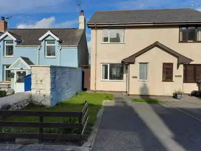 a house with a bench in front of it at King bed, opposite the beach in Borth