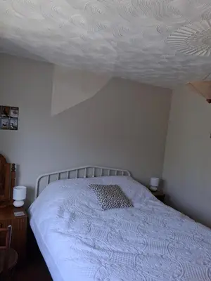 a bed in a bedroom with a ceiling at King bed, opposite the beach in Borth