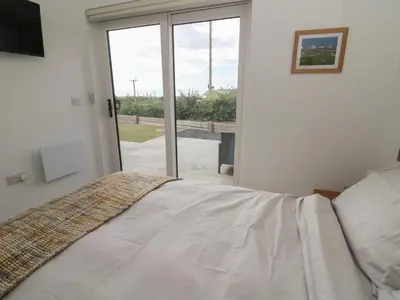 a bedroom with a bed and a sliding glass door at Rydlan in Aberystwyth