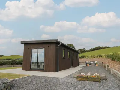 a small brown building with windows on a gravel driveway at Rydlan in Aberystwyth