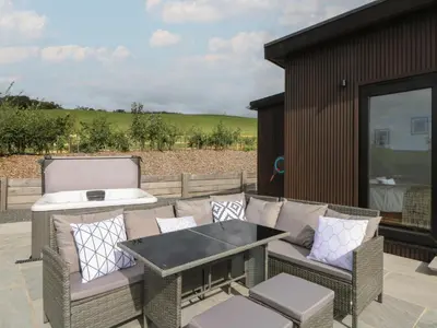 a patio with wicker chairs and a table and a grill at Rydlan in Aberystwyth