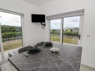 a dining room with a table and large windows at Rydlan in Aberystwyth