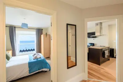 a bedroom with a bed and a view of the ocean at two bed Seafront apartment - sea views in Aberystwyth