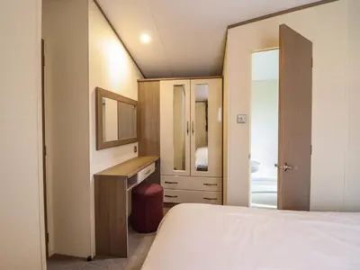 a bedroom with a bed and a dresser and a mirror at Beach Retreat E19 Dyffryn Seaside Estate in Dyffryn