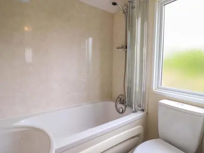 a bathroom with a tub and a toilet and a sink at Beach Retreat E19 Dyffryn Seaside Estate in Dyffryn