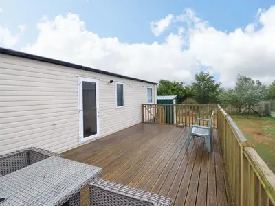 a large wooden deck next to a house at Beach Retreat E19 Dyffryn Seaside Estate in Dyffryn