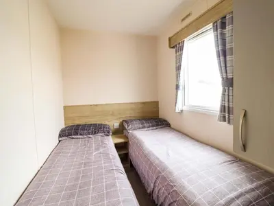 two beds in a small room with a window at Beachcombers Barmouth Bay Holiday Park in Talybont