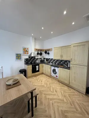 a kitchen with wooden cabinets and a table in it at Glyder Flat - North Wales in Dolgellau