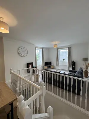 a living room with a staircase with a clock on the wall at Glyder Flat - North Wales in Dolgellau