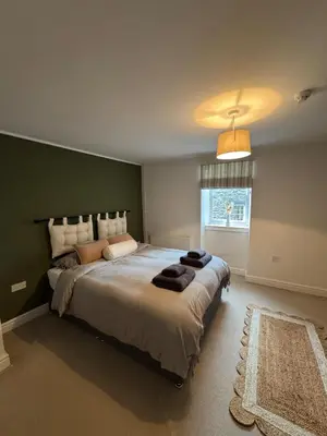 a bedroom with a large bed with a green wall at Glyder Flat - North Wales in Dolgellau