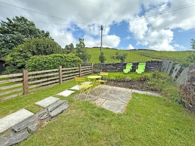 a table and chairs in a yard next to a fence at Tegfryn Cottage in Tanygrisiau