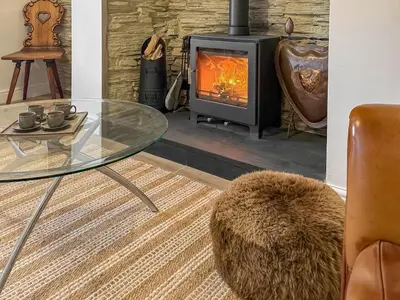 a living room with a glass table and a wood stove at Tegfryn Cottage in Tanygrisiau