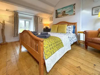 a bedroom with a wooden bed and a couch at Tegfryn Cottage in Tanygrisiau