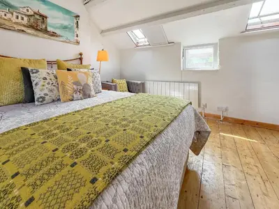 a bedroom with a large bed with a yellow blanket at Tegfryn Cottage in Tanygrisiau