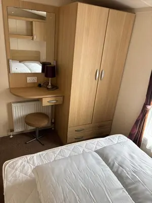 a bedroom with a bed and a cabinet and a desk at Clarach Bay Escape 3 Bedroom PetFriendly Caravan with Decking Sleeps 6 in Aberystwyth