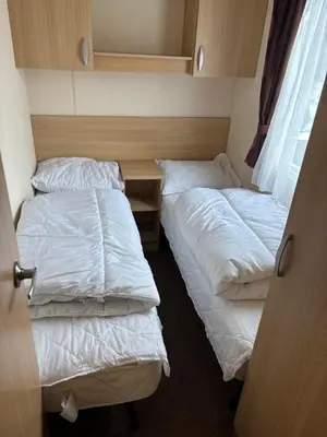 a room with two beds and a desk in it at Clarach Bay Escape 3 Bedroom PetFriendly Caravan with Decking Sleeps 6 in Aberystwyth